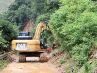 A rescue worker is driving an excavator to remove debris from a landslide at Si 'an village in Liuzhou, China, on July 2, 2024. (