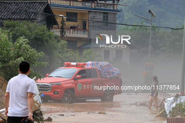 A worker is driving a vehicle to transport emergency supplies at Si 'an Village in Liuzhou, China, on July 2, 2024. 