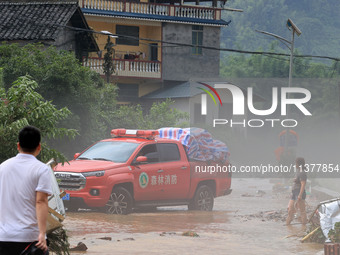 A worker is driving a vehicle to transport emergency supplies at Si 'an Village in Liuzhou, China, on July 2, 2024. (