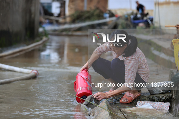 A villager is cleaning mud from a warm pot at Si 'an Village in Liuzhou, China, on July 2, 2024. 