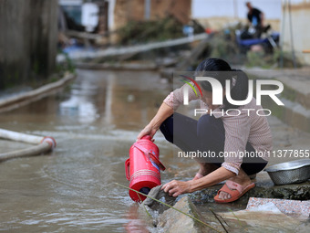 A villager is cleaning mud from a warm pot at Si 'an Village in Liuzhou, China, on July 2, 2024. (