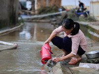 A villager is cleaning mud from a warm pot at Si 'an Village in Liuzhou, China, on July 2, 2024. (