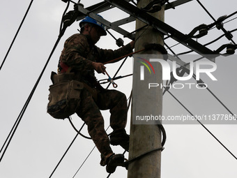 A power repair worker is working on a pole in Si 'an village, Liuzhou city, Guangxi province, China, on July 2, 2024. (