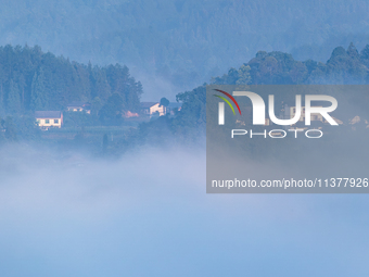 The fields, houses, mountains, and villages of Zhimu Village are appearing in the morning fog after returning farmland to forest in Chongqin...