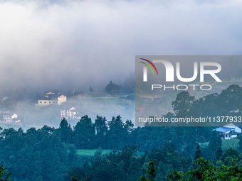 The fields, houses, mountains, and villages of Zhimu Village are appearing in the morning fog after returning farmland to forest in Chongqin...