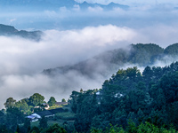 The fields, houses, mountains, and villages of Zhimu Village are appearing in the morning fog after returning farmland to forest in Chongqin...