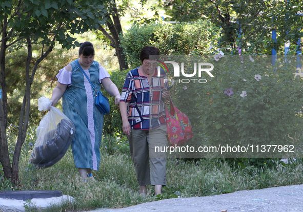 Two women affected by a recent Russian missile attack are carrying bags in Dnipro, Ukraine, on July 1, 2024. Russia is launching a missile a...