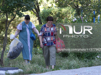 Two women affected by a recent Russian missile attack are carrying bags in Dnipro, Ukraine, on July 1, 2024. Russia is launching a missile a...