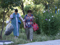 Two women affected by a recent Russian missile attack are carrying bags in Dnipro, Ukraine, on July 1, 2024. Russia is launching a missile a...