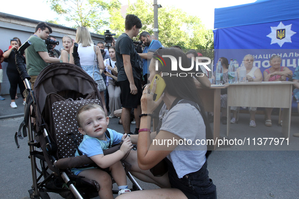 A woman is talking on the phone near a boy in a buggy at a coordination headquarters set up to help people affected by a recent Russian miss...