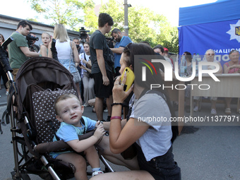 A woman is talking on the phone near a boy in a buggy at a coordination headquarters set up to help people affected by a recent Russian miss...