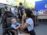 A woman is talking on the phone near a boy in a buggy at a coordination headquarters set up to help people affected by a recent Russian miss...