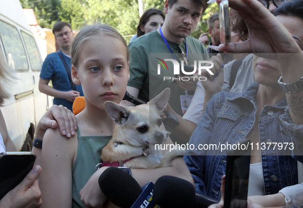 A girl affected by a recent Russian missile attack is holding a dog as she faces the press in Dnipro, Ukraine, on July 1, 2024. Russia is la...