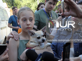 A girl affected by a recent Russian missile attack is holding a dog as she faces the press in Dnipro, Ukraine, on July 1, 2024. Russia is la...