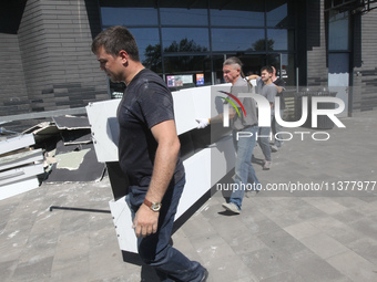 Men are carrying damaged items out of a supermarket affected by a recent Russian missile attack in Dnipro, Ukraine, on July 1, 2024. Russia...