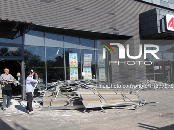 Men are carrying damaged items out of a supermarket affected by a recent Russian missile attack in Dnipro, Ukraine, on July 1, 2024. Russia...