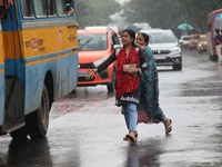 Commuters are trying to get on the passenger bus on a busy road during monsoon rain in Kolkata, India, on July 2, 2024. (