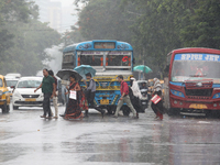 Commuters are crossing a busy road with umbrellas during monsoon rain in Kolkata, India, on July 2, 2024. (