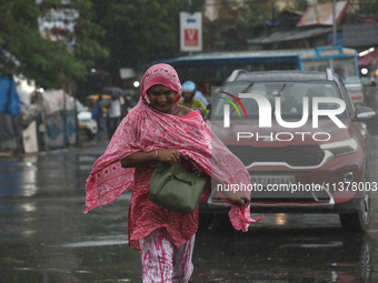 A woman is crossing a busy road during monsoon rain in Kolkata, India, on July 2, 2024. (