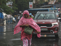 A woman is crossing a busy road during monsoon rain in Kolkata, India, on July 2, 2024. (