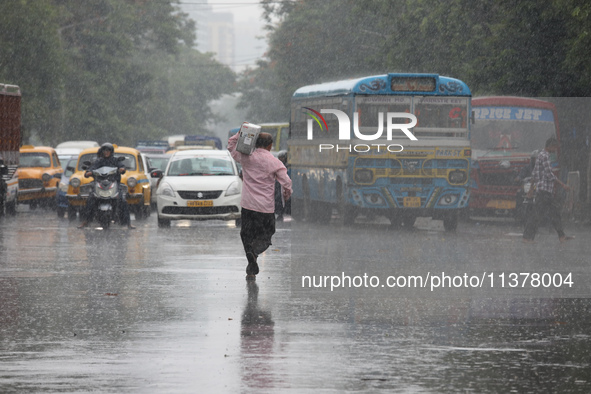 A man is crossing a busy road during monsoon rain in Kolkata, India, on July 2, 2024. 