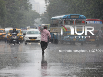 A man is crossing a busy road during monsoon rain in Kolkata, India, on July 2, 2024. (