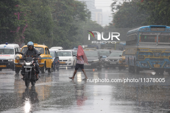 A man is crossing a busy road during monsoon rain in Kolkata, India, on July 2, 2024. 