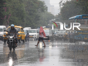 A man is crossing a busy road during monsoon rain in Kolkata, India, on July 2, 2024. (