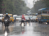 A man is crossing a busy road during monsoon rain in Kolkata, India, on July 2, 2024. (