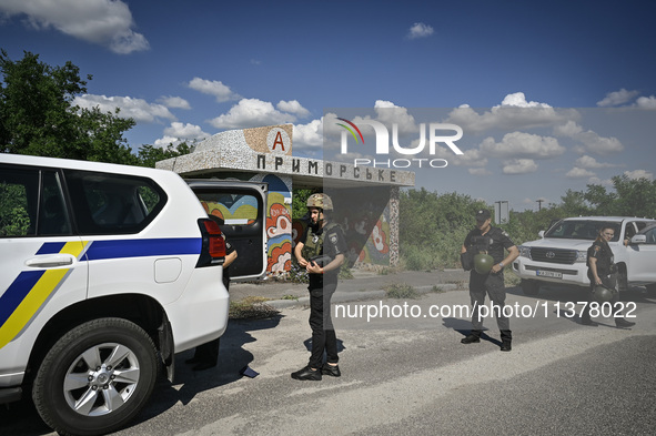 Police officers from an evacuation group are putting on personal protective equipment on their way to the rural settlement of Stepnohirsk th...