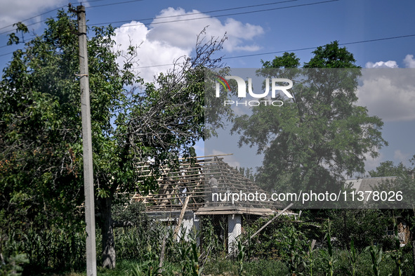 A man is repairing the roof of a house in the rural settlement of Stepnohirsk, Ukraine, on June 28, 2024, as the team of Zaporizhzhia police...