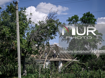 A man is repairing the roof of a house in the rural settlement of Stepnohirsk, Ukraine, on June 28, 2024, as the team of Zaporizhzhia police...