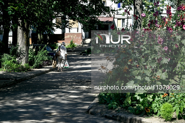 An elderly woman is carrying bags towards an apartment block in the rural settlement of Stepnohirsk, Ukraine, on June 28, 2024, which is bei...