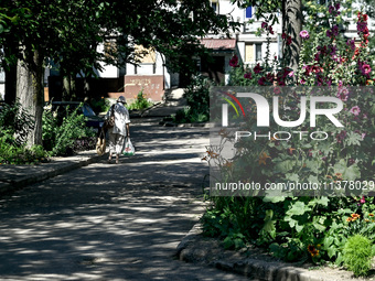 An elderly woman is carrying bags towards an apartment block in the rural settlement of Stepnohirsk, Ukraine, on June 28, 2024, which is bei...