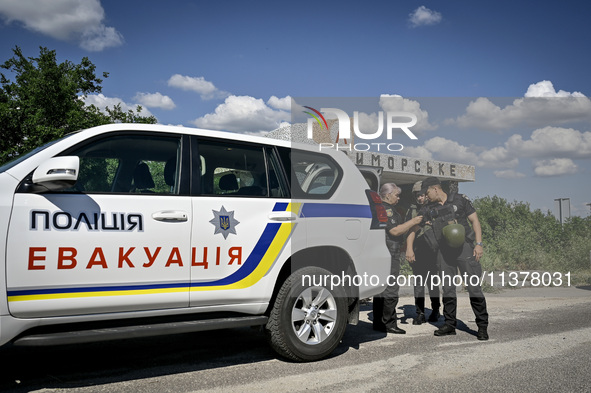 Police officers from an evacuation group are putting on personal protective equipment on their way to the rural settlement of Stepnohirsk th...