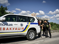 Police officers from an evacuation group are putting on personal protective equipment on their way to the rural settlement of Stepnohirsk th...