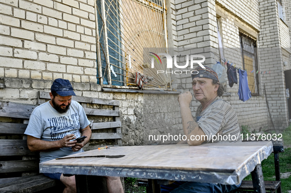 Locals are sitting at the table outside an apartment block in the rural settlement of Stepnohirsk, Ukraine, on June 28, 2024, which is being...