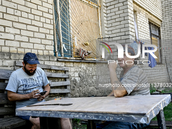 Locals are sitting at the table outside an apartment block in the rural settlement of Stepnohirsk, Ukraine, on June 28, 2024, which is being...