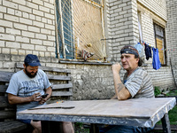 Locals are sitting at the table outside an apartment block in the rural settlement of Stepnohirsk, Ukraine, on June 28, 2024, which is being...