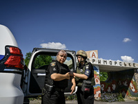 Police officers from an evacuation group are putting on personal protective equipment on their way to the rural settlement of Stepnohirsk th...