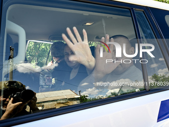 Locals Volodymyr and Iryna are waving from inside a police car during the evacuation from the rural settlement of Stepnohirsk that is being...