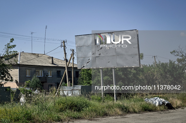 A hoarding dotted by shrapnel holes is being pictured in the rural settlement of Stepnohirsk that is being shelled daily by Russian troops a...