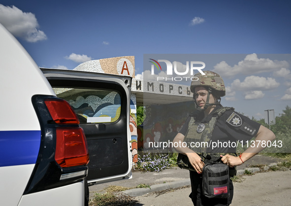 A police officer from an evacuation group is putting on personal protective gear on the way to the rural settlement of Stepnohirsk that is b...