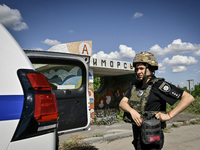 A police officer from an evacuation group is putting on personal protective gear on the way to the rural settlement of Stepnohirsk that is b...