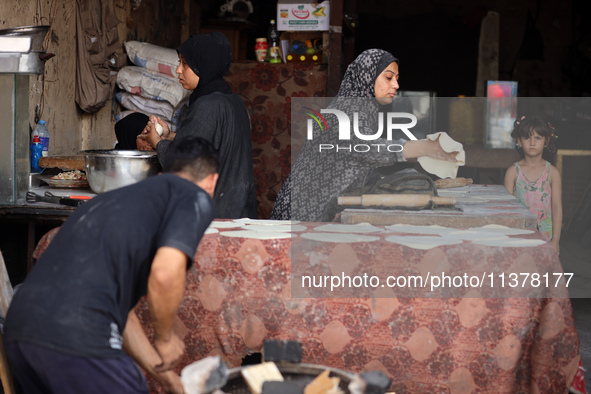 A displaced Palestinian woman is preparing flatbread dough at a stall kitchen in Deir el-Balah in the central Gaza Strip on July 2, 2024, am...