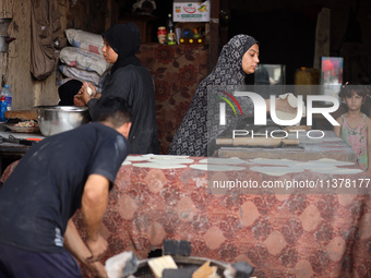 A displaced Palestinian woman is preparing flatbread dough at a stall kitchen in Deir el-Balah in the central Gaza Strip on July 2, 2024, am...