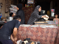 A displaced Palestinian woman is preparing flatbread dough at a stall kitchen in Deir el-Balah in the central Gaza Strip on July 2, 2024, am...