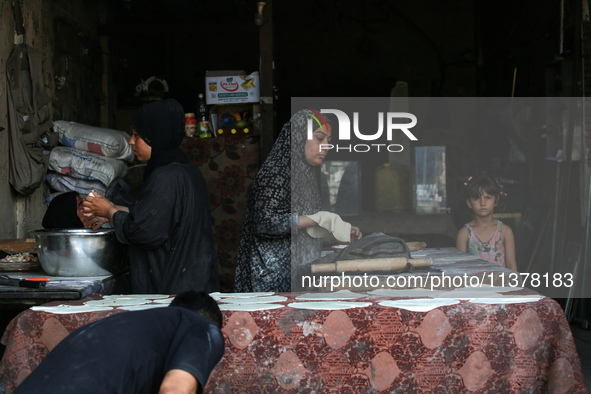 A displaced Palestinian woman is preparing flatbread dough at a stall kitchen in Deir el-Balah in the central Gaza Strip on July 2, 2024, am...