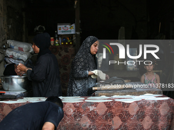 A displaced Palestinian woman is preparing flatbread dough at a stall kitchen in Deir el-Balah in the central Gaza Strip on July 2, 2024, am...