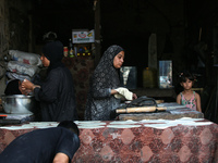 A displaced Palestinian woman is preparing flatbread dough at a stall kitchen in Deir el-Balah in the central Gaza Strip on July 2, 2024, am...